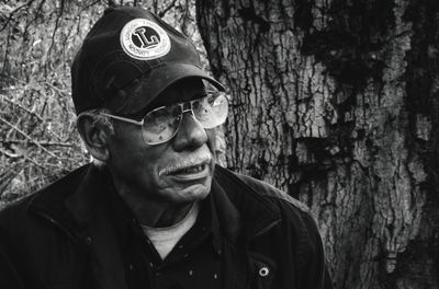 Portrait of man wearing sunglasses against tree trunk
