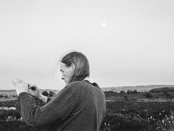 Mature woman standing on grassy field against sky