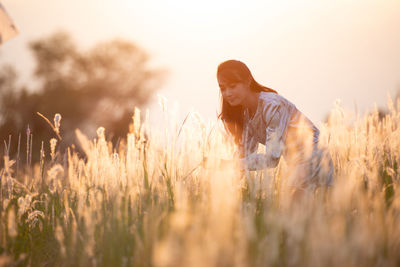 Woman standing on field against sky during sunset