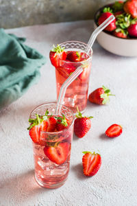 Two glasses with a strawberry cocktail and a bowl of berries on the table. homemade drinks