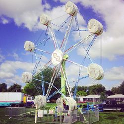 Low angle view of ferris wheel against cloudy sky