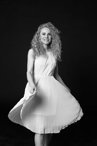 Portrait of a smiling young woman against black background
