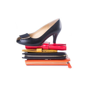 Close-up of high heels on clutch bags against white background