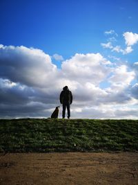 Man with dog on grass against sky