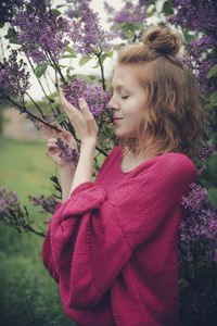 Woman standing by purple flowering plants