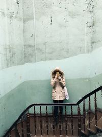 High angle view of woman holding smart phone against wall on steps