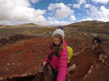 Portrait of smiling young woman standing on landscape against sky