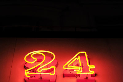 Low angle view of illuminated number 24 on red wall