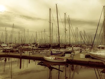 Sailboats moored at harbor against sky during sunset