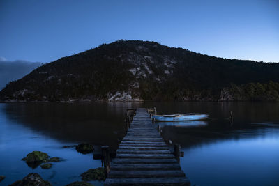Scenic view of lake and mountains against clear blue sky