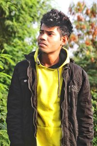 Portrait of young man standing against plants