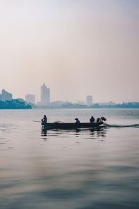 People on boat in sea against sky