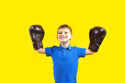 Portrait of smiling boy standing against yellow background