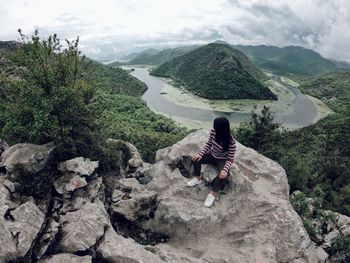 Rear view of person on rock against mountains