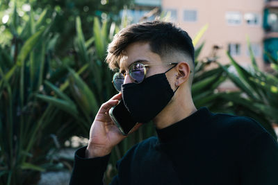 Boy with sunglasses and mask calls on the phone
