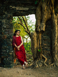 Portrait of woman standing by a tree trunk.
