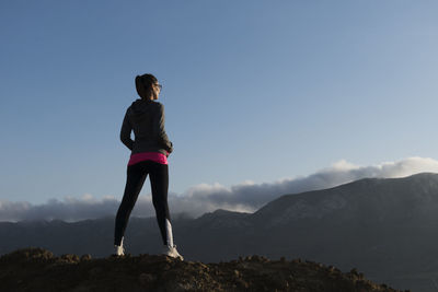 Rear view of woman standing on mountain against sky