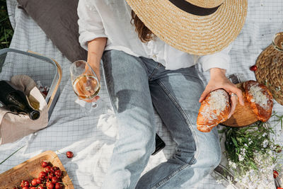 Woman in straw hat on picnic holding a glass of wine top view. aesthetic picnic 