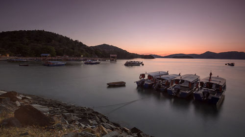 Boats in calm sea at sunset