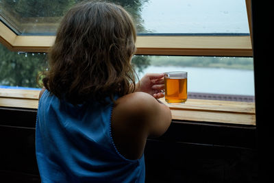 Rear view of woman sitting at window