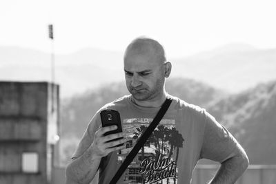 Man using mobile phone against sky