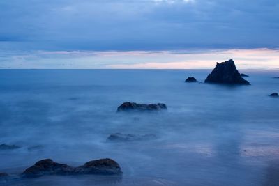 Rock formation in sea against sky