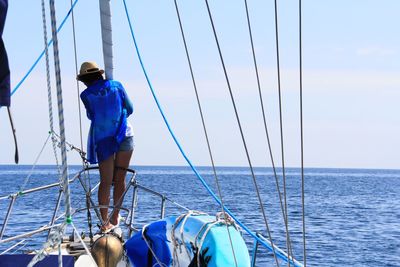 Rear view of woman standing on boat in sea against sky