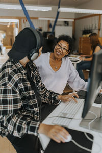 Smiling teacher looking at young male student in computer lab