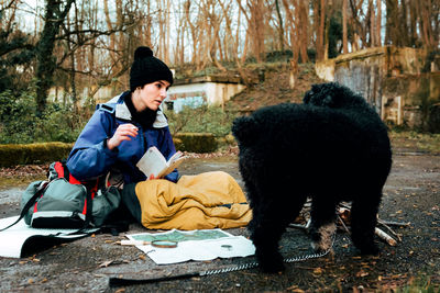 Young female backpacker making notes at campfire
