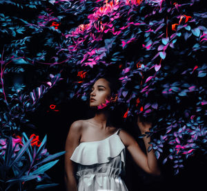 Portrait of young woman standing against plants