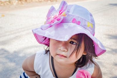 Close-up of cute baby girl wearing pink hat looking away on road