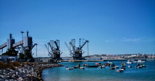 Cranes at harbor against clear sky