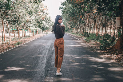 Full length of young woman standing on road