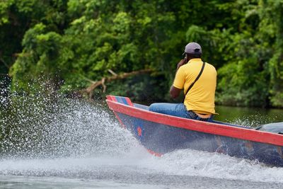 Rear view of man on boat in river