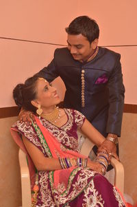 Smiling young couple looking at each other against wall