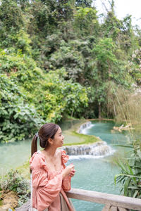 Side view of woman looking away while standing in forest