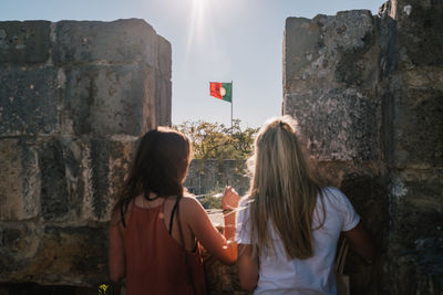 Rear view of women standing by surrounding wall