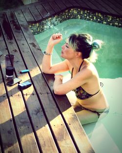 High angle view of woman smoking cigarette while sitting in swimming pool