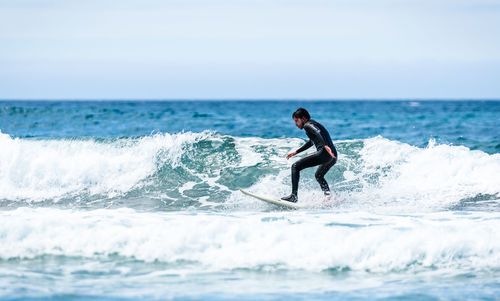 Man surfing in sea against sky