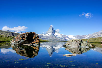 Scenic view of lake and mountains against blue sky