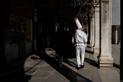 Rear view of woman walking on tiled floor in building