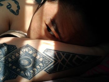Close-up of tattooed woman relaxing in darkroom