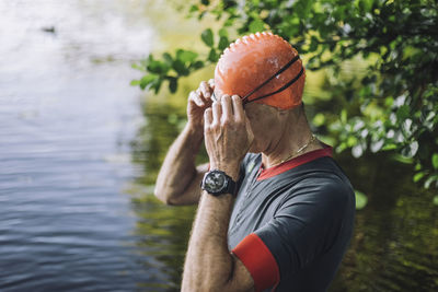 Mature man adjusting swimming goggles in lake