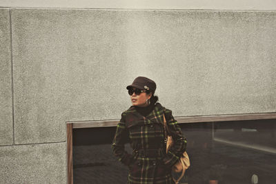 Portrait of young woman standing against wall