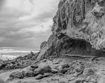 Rock formation on beach against sky