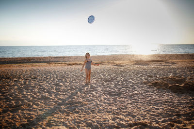 Rear view full length of kid standing at beach