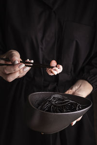 Woman holding a plate with spaghetti with cuttlefish ink and octopus