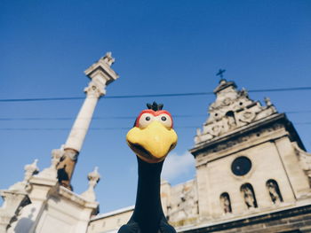 Low angle view of statue against building against clear blue sky