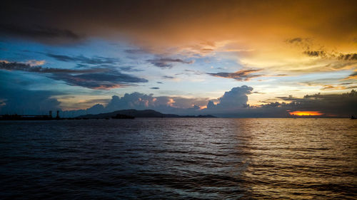 Scenic view of sea against dramatic sky during sunset