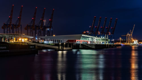 Illuminated pier over river against sky at night